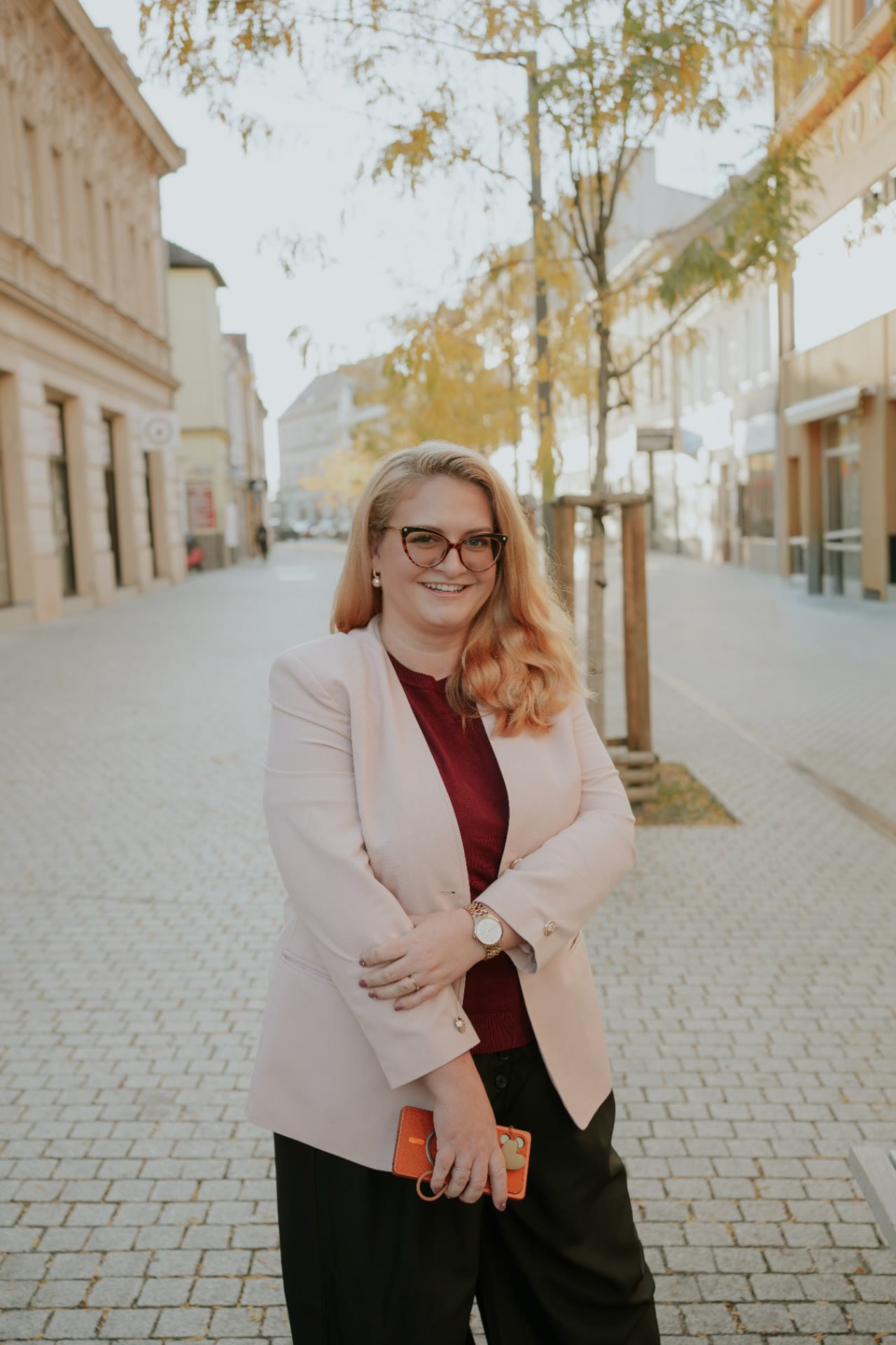 Katka Géringová v růžovém saku v ulici s telefonem